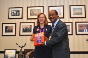 Olympian Katie Ledecky and County Executive Ike Leggett share a light moment over the Ike's picture on a Wheaties Box