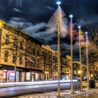 New Years moon above Main Street Park and Pavilion flag poles in the Kentlands as car streaks by.